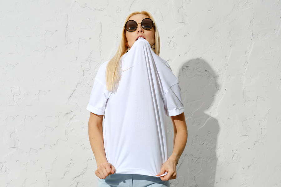 Une femme qui croque dans son tee-shirt pour couper un fil cousu sur son t-shirt