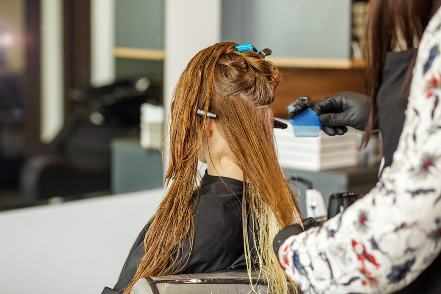 Une coloriste qui applique la a patine Dialight de L'Oréal sur les cheveux secs de sa cliente