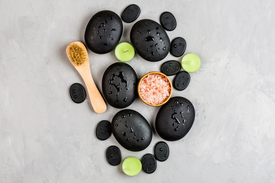 Des pierres chaudes noires avec un brosse et des bougies vert clair