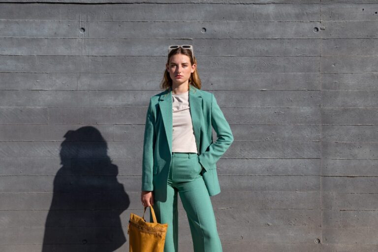 Blazer vert porté par une femme, avec un pantalon vert, une lunette et un sac marron
