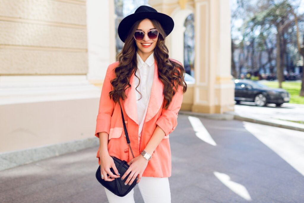 Une femme qui porte un blazer orange avec une chemise et un pantalon blanc
