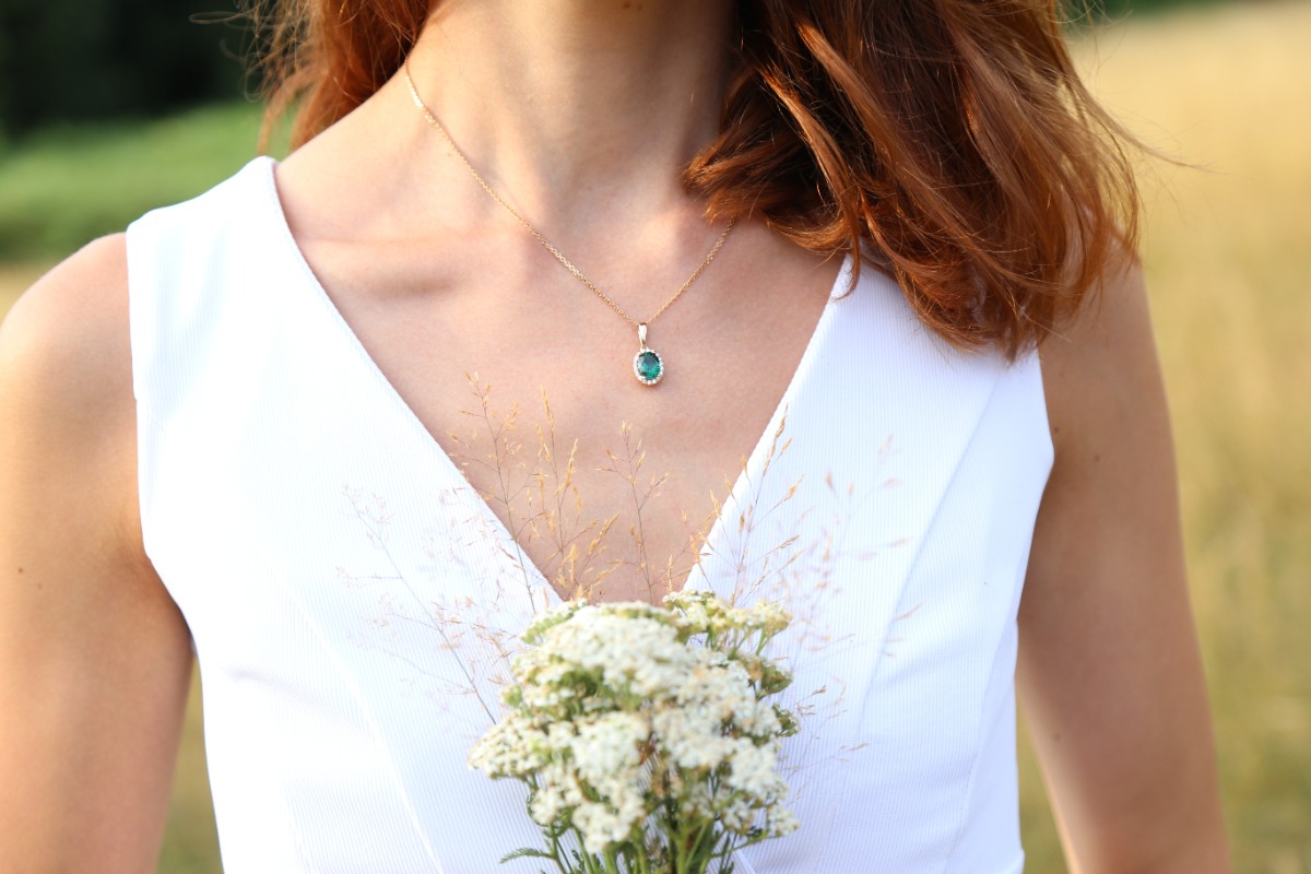 Une femme qui porte une robe en col v blanche et un collier