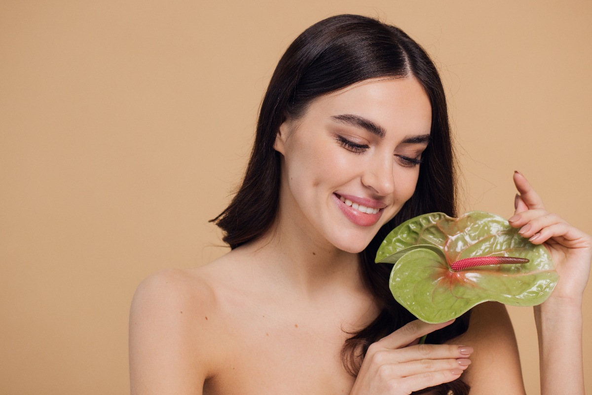 Une belle femme souriante qui tient une feuille d'orchidé