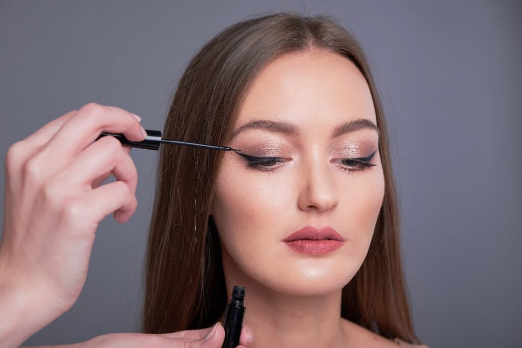 Une maquilleuse appliquant du eyeliner sur les yeux d'une femme