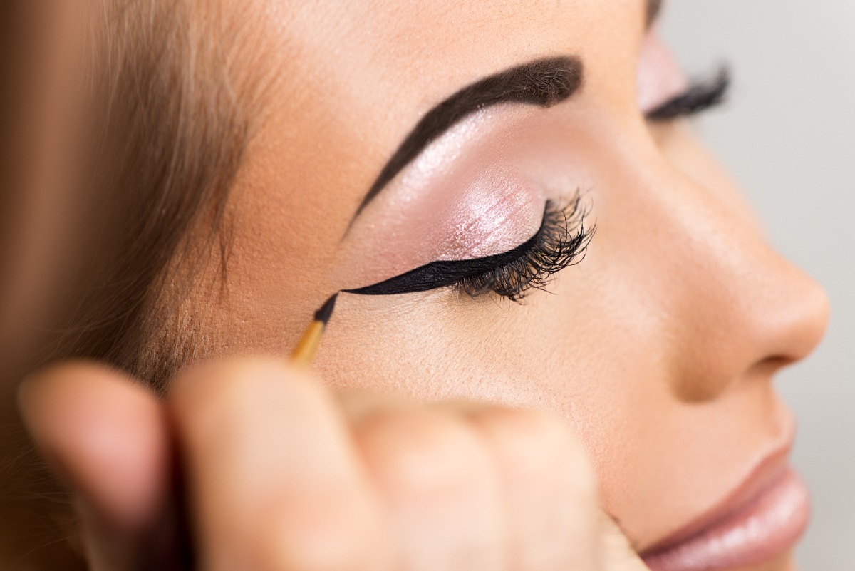 Une femme mettant du eyeliner aux yeux avec des faux cils magnétiques