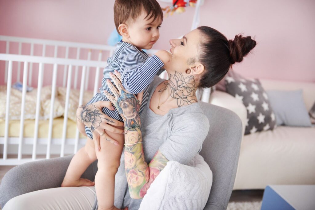 Une jeune mère qui allaite et qui a des tatouges sur les bras