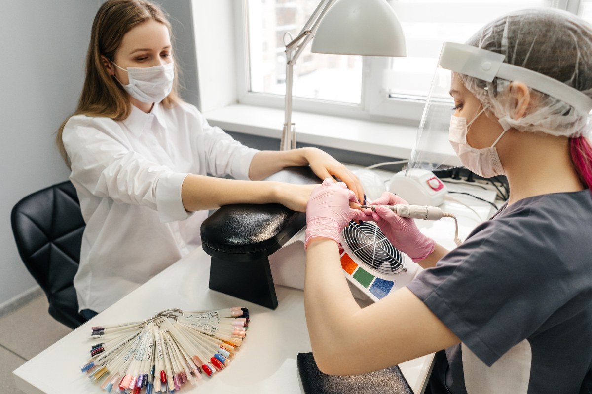 Une esthéticienne travaillant dans un institut, et posant un vernis semi-permanent pour une cliente