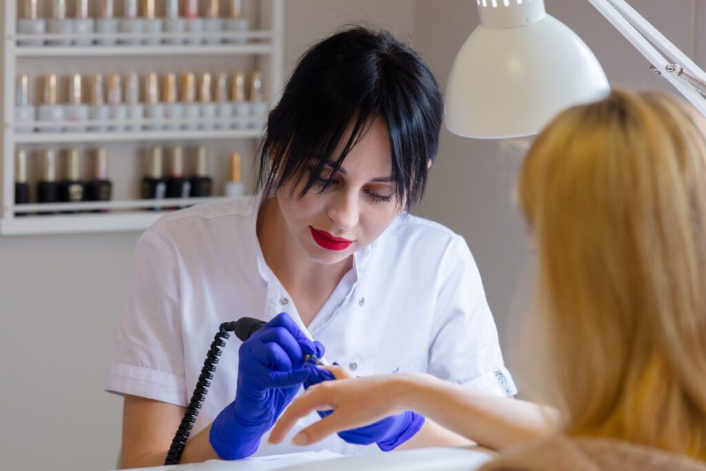 Une professionnelle réalisant une pose de vernis semi-permanent