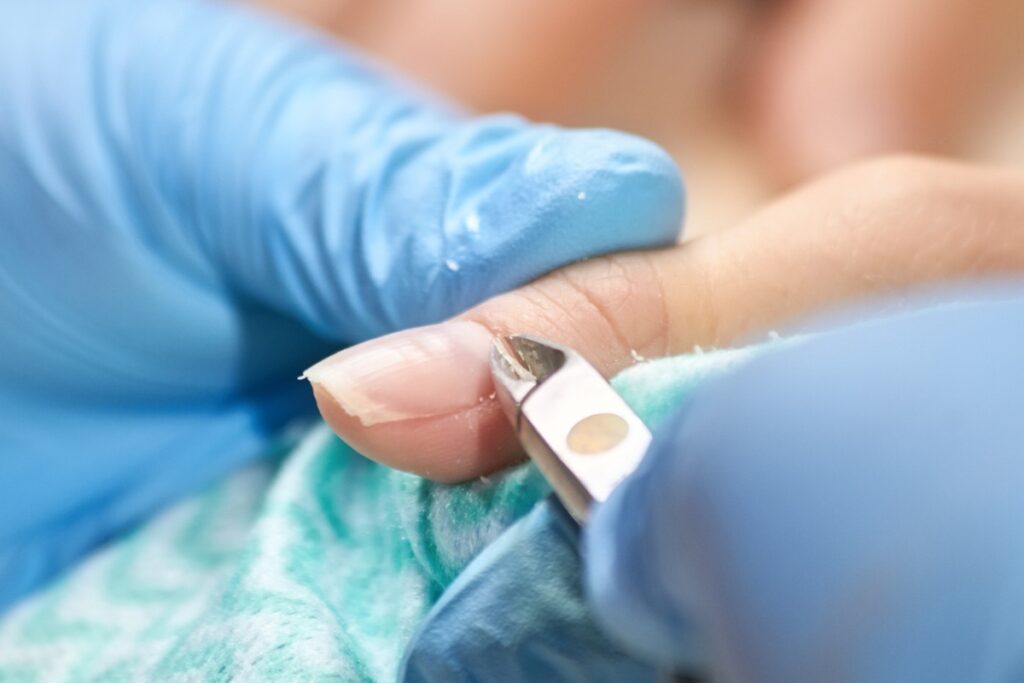 Une estheticienne qui enlève du cuticule sur l'ongle d'une femme