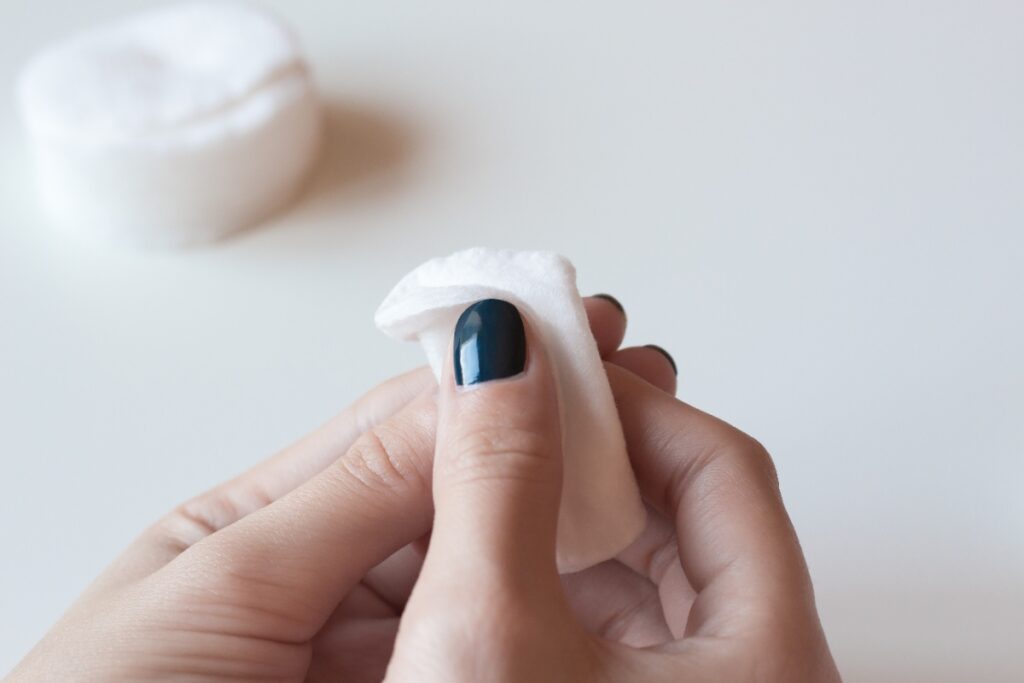 Une personne qui applique du disolvant sur ses ongles