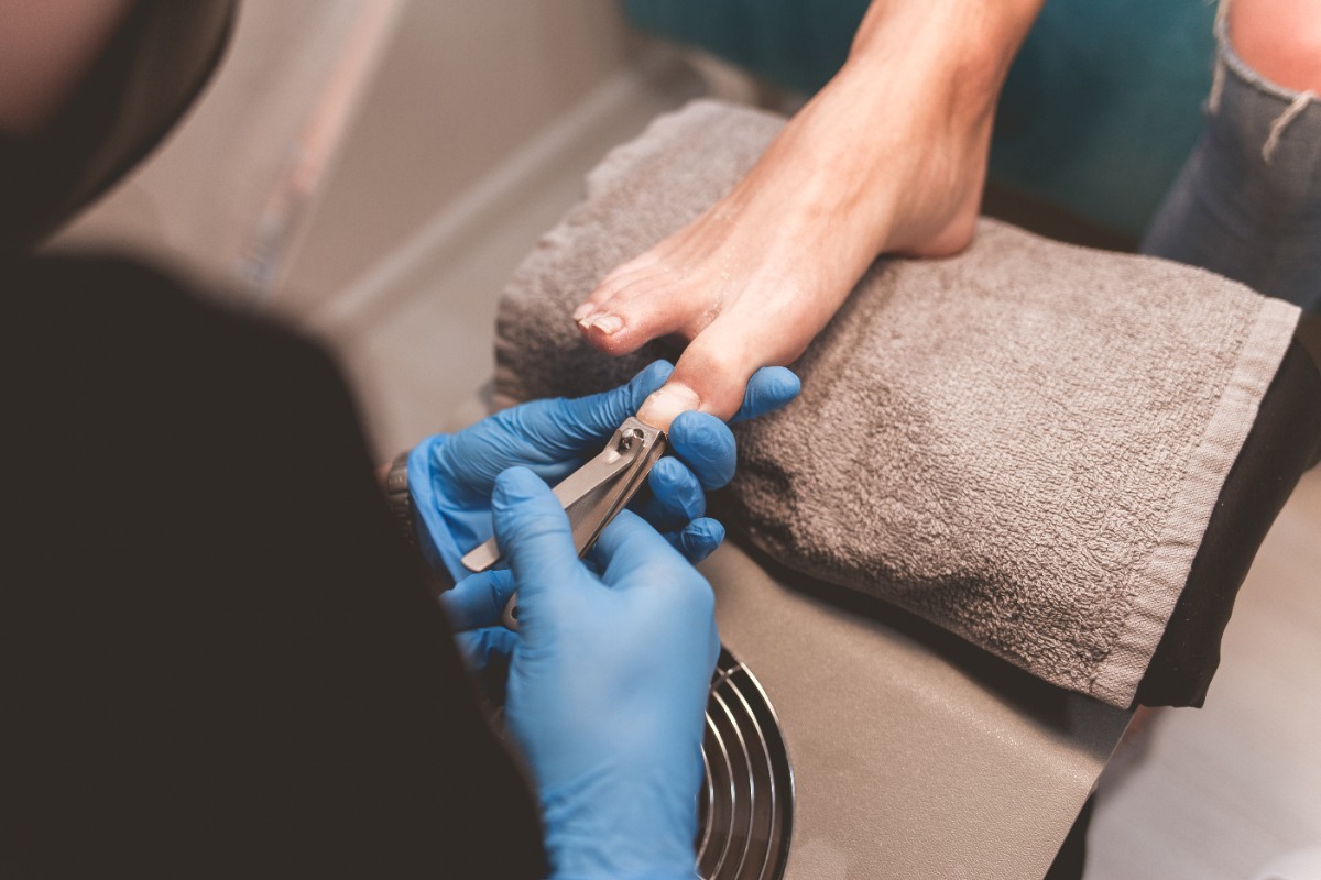 Une personne portant un gant et coupe les ongles des pieds