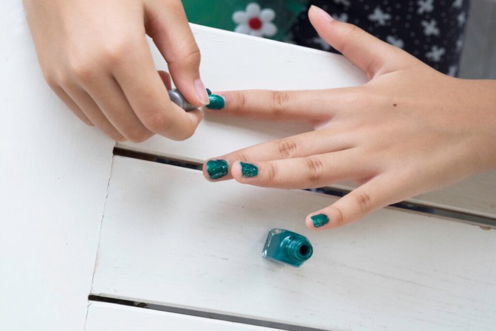 Une femme qui met du vernis à ongle de couleur vert
