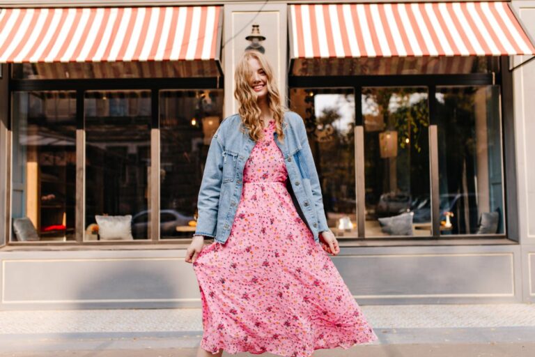 Une femme habillée en robe fleurie longue et une veste jean bleue