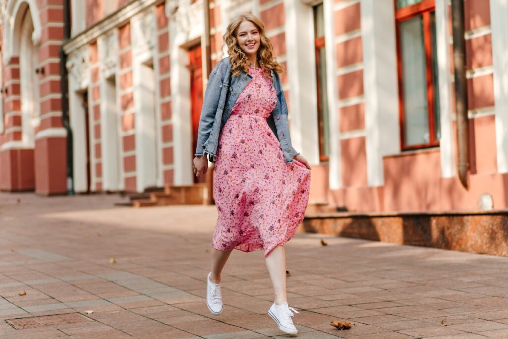 Une femme habillée en robe longue, veste jean et basket