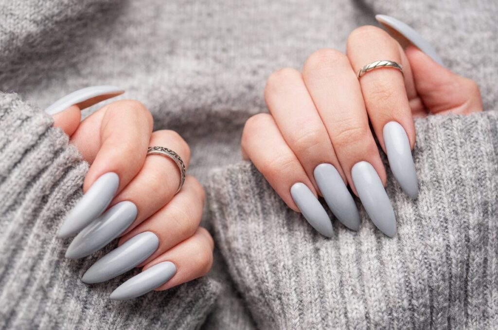 Mains avec des ongles longs aux vernis gris