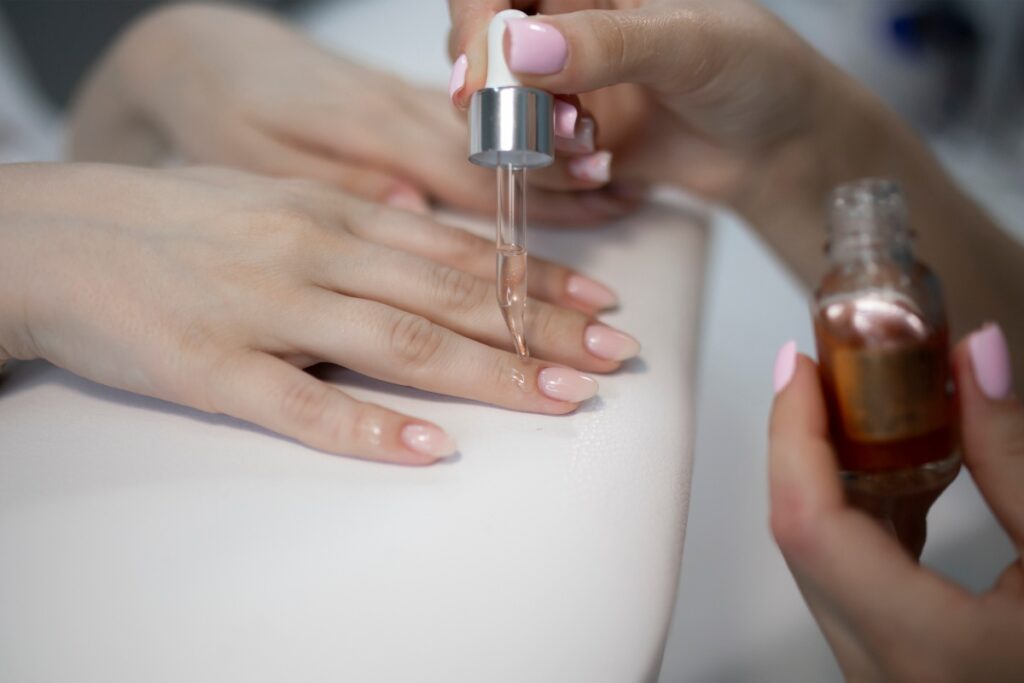 Une personne versant de l'huile de ricin sur les ongles