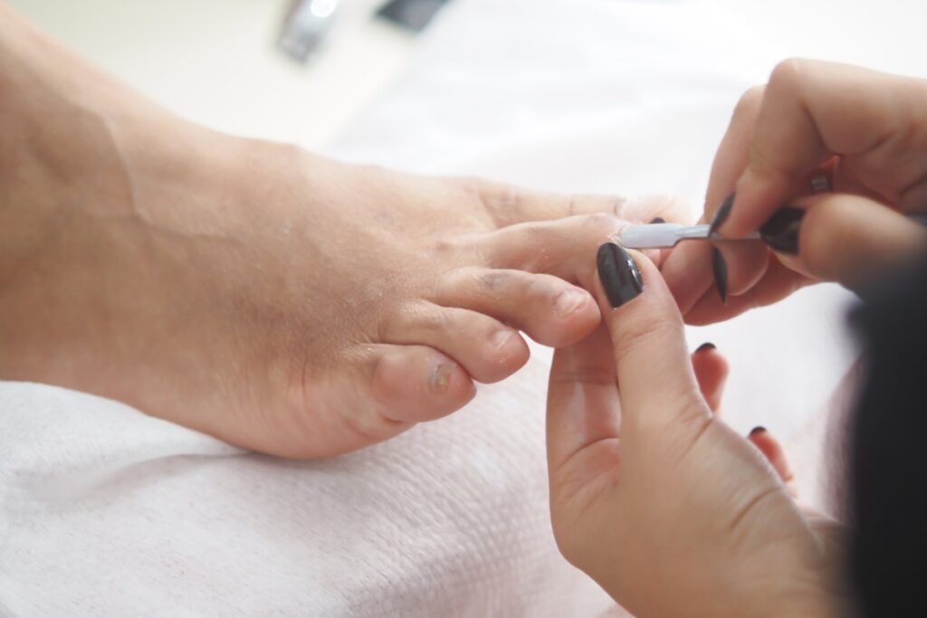 Une personne faisant un soin pour les ongles du pieds