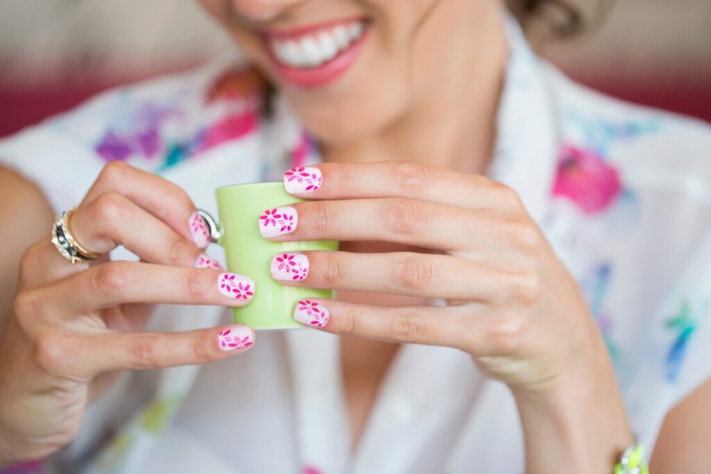 Une femme souriante avec des ongles à motif floral