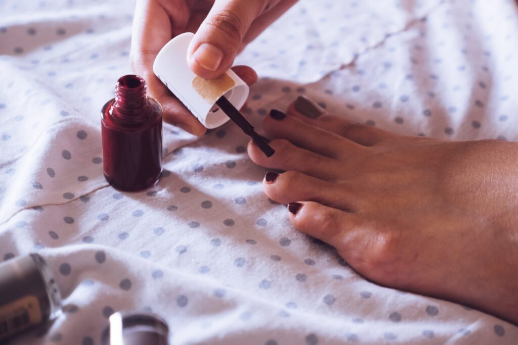 Une femme vernissant ses ongles de pieds