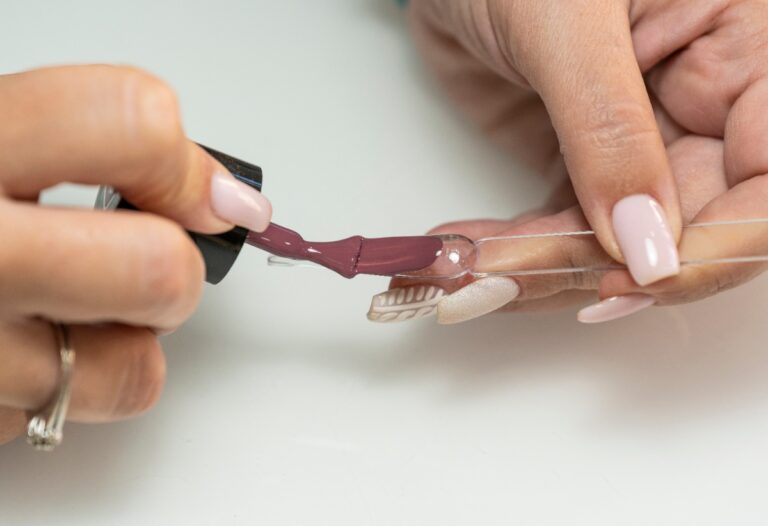 Mains appliquant du vernis sur du faux ongles