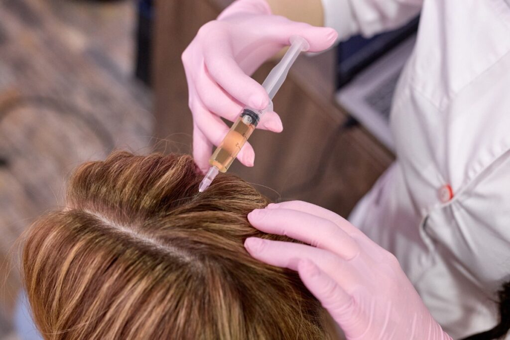 Une femme appliquant de l'huile aux cheveux