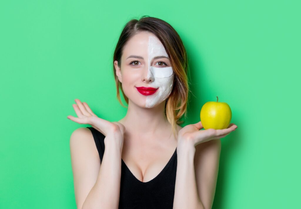 Une femme avec du masque au visage et tient une pomme