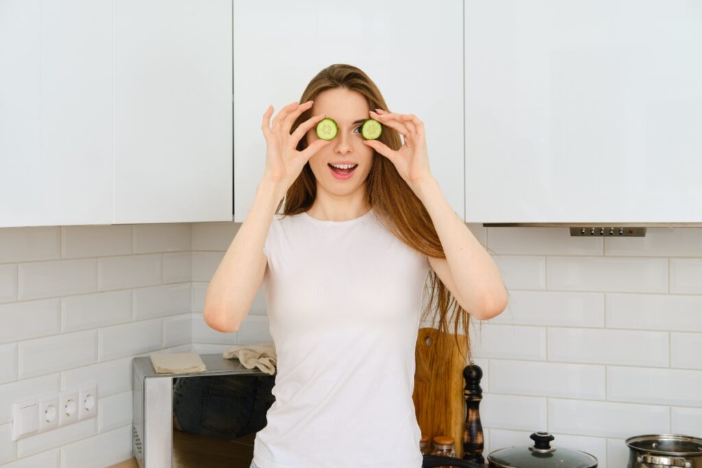 Une femme mettant des tranches de concombres sur les yeux