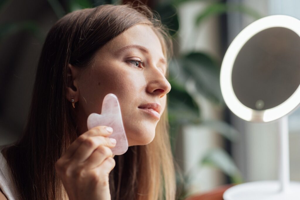 Une femme qui utilise du guasha devant un miroir