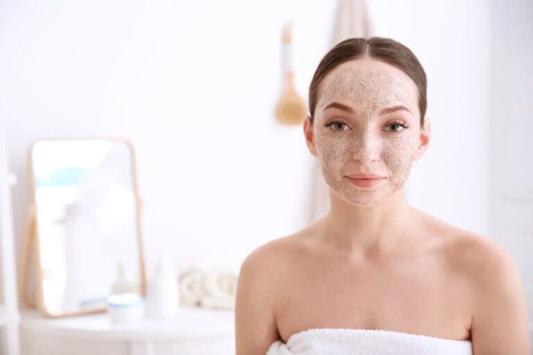 Femme souriante en faisant du soin sur son visage à cause de sa peau granuleuse