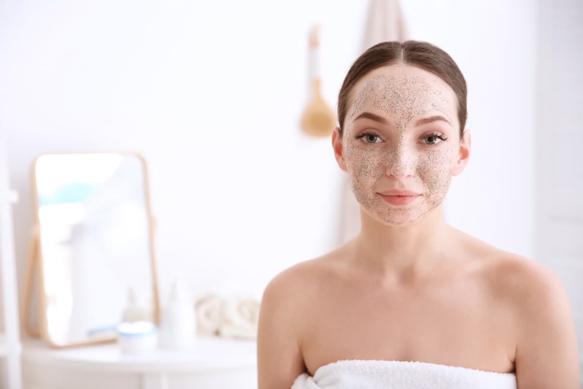 Femme souriante en faisant du soin sur son visage à cause de sa peau granuleuse